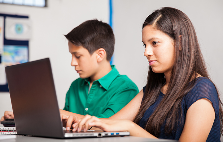 Dos niños de secundaria en computadoras portátiles