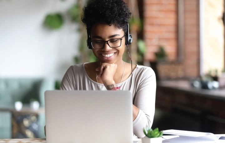 Woman sitting at computer with headphones smiling