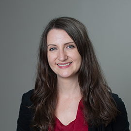 Allison Rizzolo Headshot - smiling woman with red blouse in front of grey backdrop