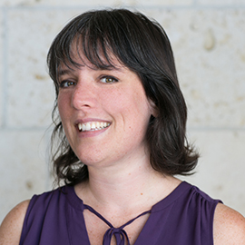 Headshot of Whitney Beissner -Smiling brunette against stone wall