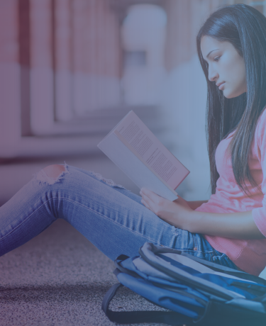 Joven mujer sentada y leyendo en un campus universitario