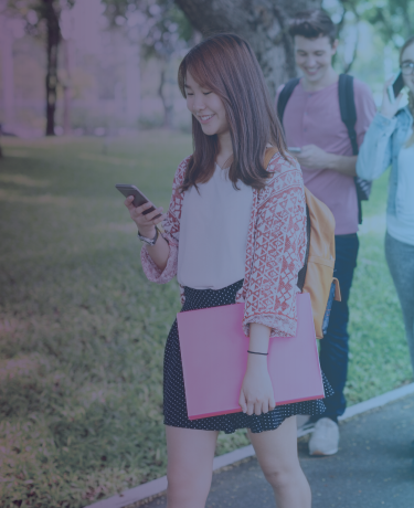 Mujer joven caminando por el campus de la escuela usando su teléfono