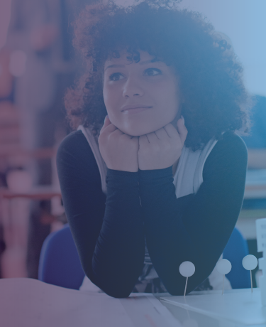 Young girl at school desk looking dreamily offscreen