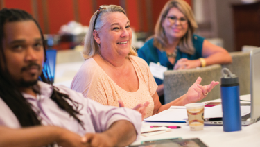 Three counselors smiling and laughing at work table