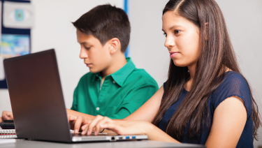 Two latino children at laptops