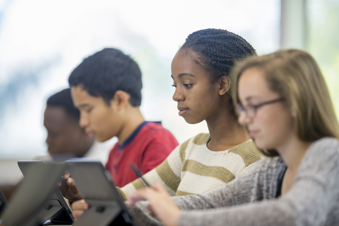 Estudiantes diversos leyendo en tabletas