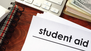 Student aid application on a desk near a keyboard and money